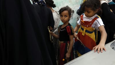 Två barn köar för att få mathjälp i svältdrabbade Jemen