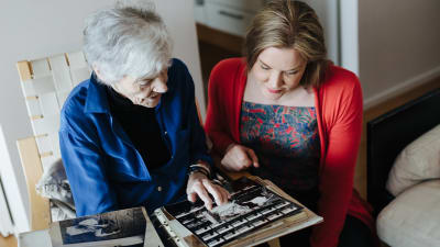 Märta Tikkanen och Johanna Holmström tittar på gamla fotografier.