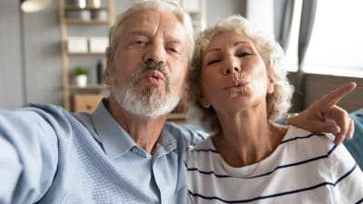 Äldre man och kvinna gör pussmunnar mot kameran