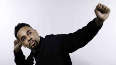 Närbild på Julian Owusu som står med händerna ut och tittar upp mot taket.