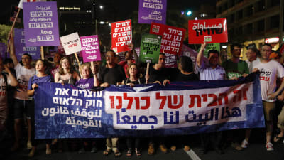 Israeler i Tel Aviv protesterar mot den nya nationalstatslagen. På en stor banderoll står det "Det här huset tillhör oss alla" på Hebreiska.