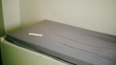 En fjärrkontroll ligger på sängen i en cell.