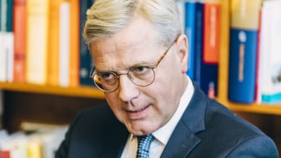 Norbert Röttgen i kostym och glasögon sitter framför en bokhylla.