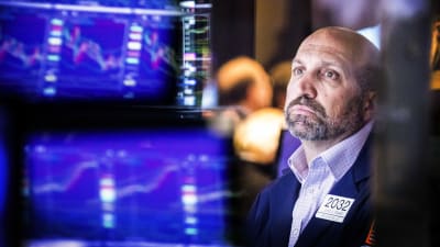 En man sitter och tittar på dataskärmar inne i Wall Street-byggnaden.