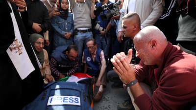 Journalisten Shireen Abu Akleh som dödats av israeliska soldater ligger på marken med journalistväst och den palestinska flaggan ovanpå.