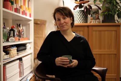 Bild av en kvinna som sitter med en kaffekopp i handen.