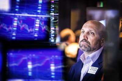 En man sitter och tittar på dataskärmar inne i Wall Street-byggnaden.