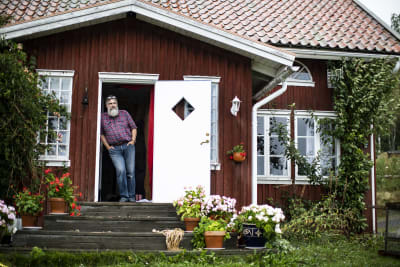 Patrick Sellman står vid dörren till sitt röda hus.