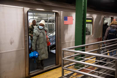 Kvinna med ansiktsskydd stiger av metron i New York