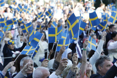 En stor folksamling som viftar med svenska flaggor.