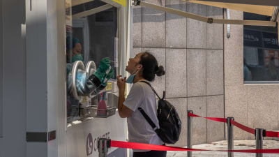 En kvinna coronatestas på en tågstation i Peking.