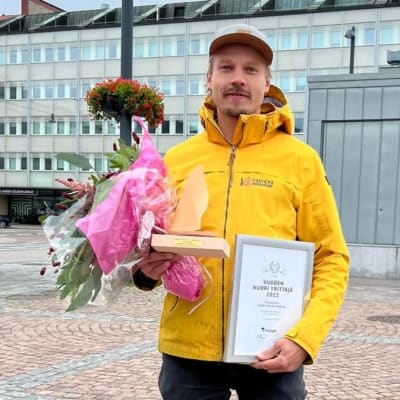 Lahden Nuori yrittäjä 2022 Vilho Koskinen Lahden torilla. Sylissään hänellä on todistus valinnasta sekä kukkia.