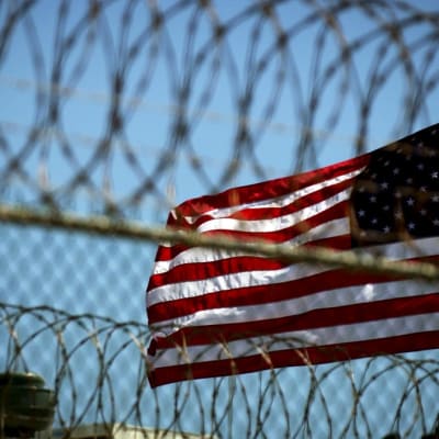 Yhdysvaltain lippu liehuu Guantanamon piikkilanka-aidan takana. 