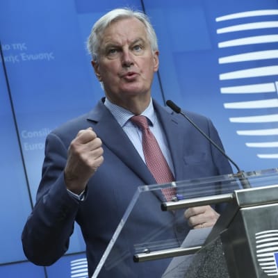 Kuvassa Michel Barnier puhujanpöntön takana. Taustalla EU:n symboli.