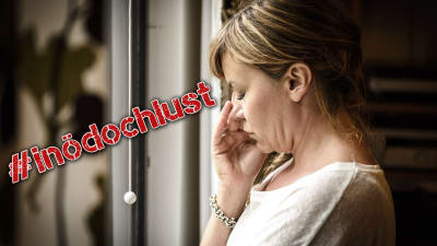 Ledsen kvinna framför fönster med #inödochlust