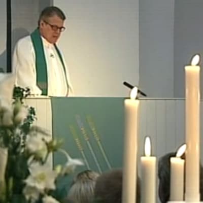 Pappi pitää Myyrmannin pommi-iskussa kuolleille muistotilaisuutta Myyrmäen kirkossa 20.10.2002, ohjelmasta Muistohartaus Myyrmäen kirkossa Vantaalla.