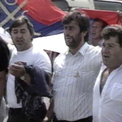 Serbimiehiä kävelemässä kadulla lippu mukanaan
