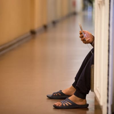Kuvassa näkyy kännykkää näppäilevä turvapaikanhakijan käsi vastaanottokeskuksessa Saksan Wilmersdorfissa. 