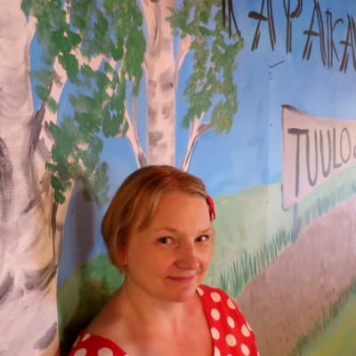 Nuori nainen seisoon seinämaalauksen edessä jossa lukee Kapakanmäki