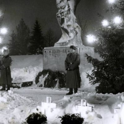 kaksi sotilasta asennossa sankaripatsaan edessä
