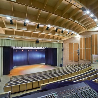 En konsertsal med flera hundra platser. träkonstruktioner, bänkar i trä och blått, belyst scen.
