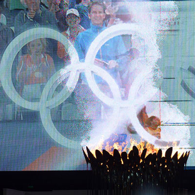 Olympiatuli palamassa kenttätapahtumia esittävän jättinäytön edustalla Lontoon olympiastadionilla.
