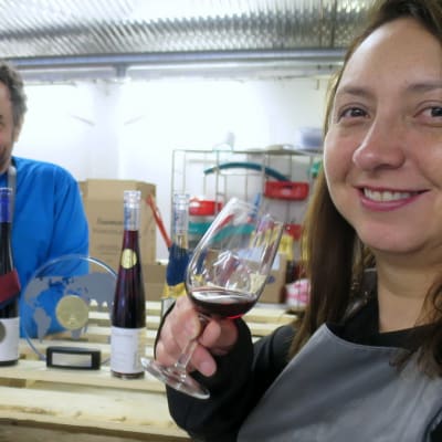 Mies tuosuttelee viini lasissa ja nainen hymyilee etualalla lasi kädessään