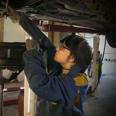 Nuori nainen korjaa autoa.