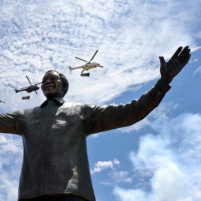 Helikopterit kantavat kansallislippuja, kun Nelson Mandelan yhdeksänmetrinen pronssipatsas paljastetaan Pretoriassa, Etelä-Afrikassa 16. joulukuuta 2013.