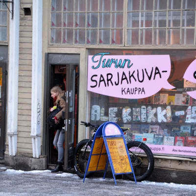 Asiakas kävelee ulos Turun Sarjakuvakaupasta.