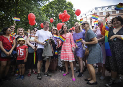 Statsminister Sanna Marin viftar med en regnbågsflagga tillsammans med människor som firar Helsinki Pride. 