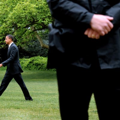Yhdysvaltain presidentti Barack Obama kävelee Valkoisen talon nurmikolla Salaisen palvelun miehen tarkkaillessa ympäristöä.