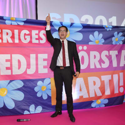 Jimmi Åkesson käsi ylhäällä lakanan edessä, jossa lukee Sveriges tredje största parti.
