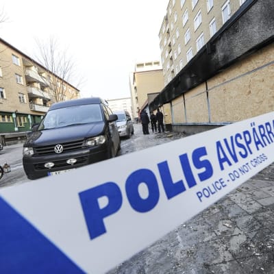 Poliisin eristysnauha kadulla, taustalla auto.