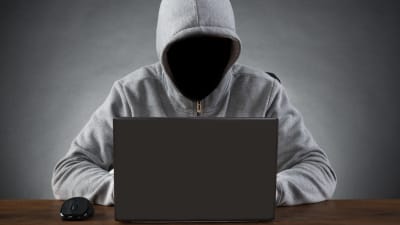 Anonym person framför en laptop