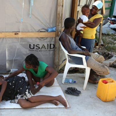 Koleraoireista kärsivä nainen makaa maassa Haitissa.