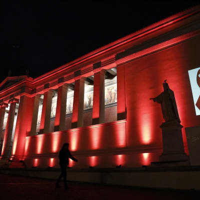Ateenan yliopiston julkisivu on punainen aids-päivän kunniaksi.