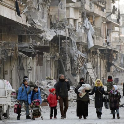 Ihmisiä kävelee talonraunioiden keskellä Aleppossa.