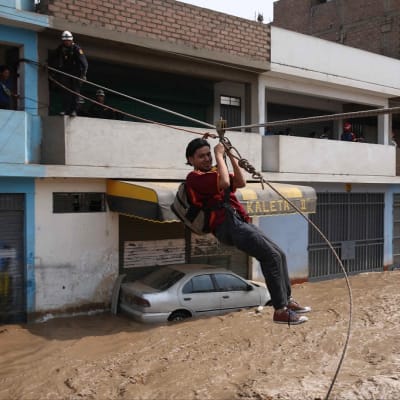 Perun poliisi pelastaa ihmisiä tulvan tieltä maan pääkaupunki Limassa 17.3.2017.