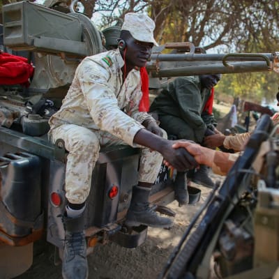 Malilaissotilas istuu auton päällä ja kättelee ranskalaissotilasta