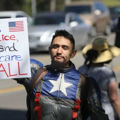 Trumpin vastainen mielenosoittaja pitää kylttiä kädessään Kaliforniassa. Kyltin teksti vaatii vapautta, oikeutta ja terveydenhuoltoa kaikille.