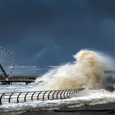 Kuvassa korkea myrskyaalto Britannian Blackpoolissa. Kuvassa taustalla vasemmassa laidassa on maailmanpyörä. 