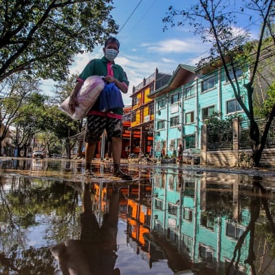 Mies seisoo veden peittämällä kadulla. Talojen julkisivut heijastuvat veteen.