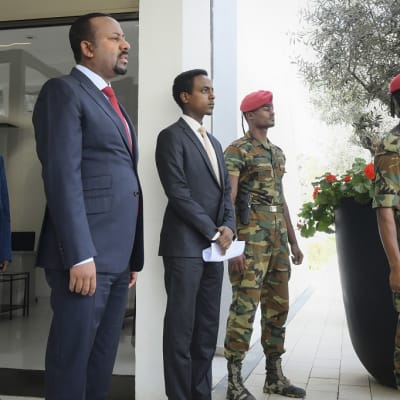 Kuvassa etualalla seisoo Etiopian pääministeri Abiy Ahmed. Hänen oikealla puolellaan on kaksi sotilasta. Lisäksi kuvassa on kaksi miestä, jotka ovat ilmeisesti Abiyn avustajia. Toinen on hänen oikealla ja toinen vasemmalla puolellaan. 