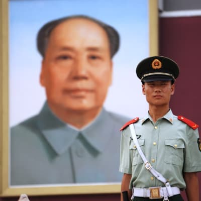 Kiinalainen sotilas Maon kuvan edessä.