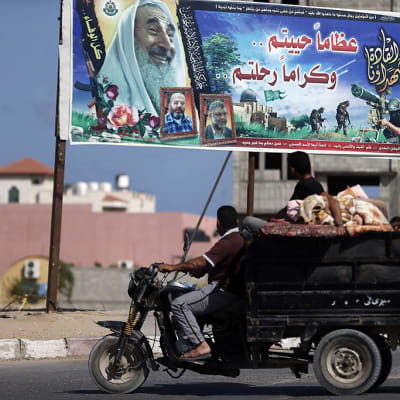 Palestiinalaiset ohittivat Hamasin propagandajulisteen palatessaan YK:n suojapaikasta takaisin koteihinsa Gazassa 14. heinäkuuta 2014. 