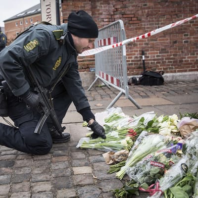 Poliisi laskee kukkia maahan.