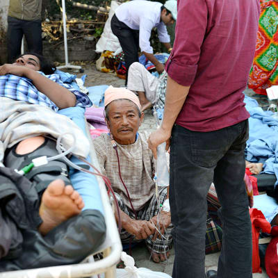 Maanjäristyksen uhreja makaa sängyillä avoimella alueella.