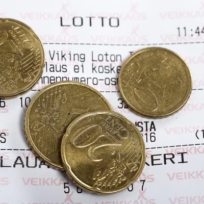 Kolikoita lottokupongin päällä.