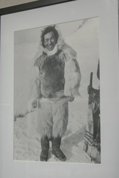 Mustavalkoinen arkistokuva kehyksissä, hymyilevä mies turkisasussa, taustalla lunta